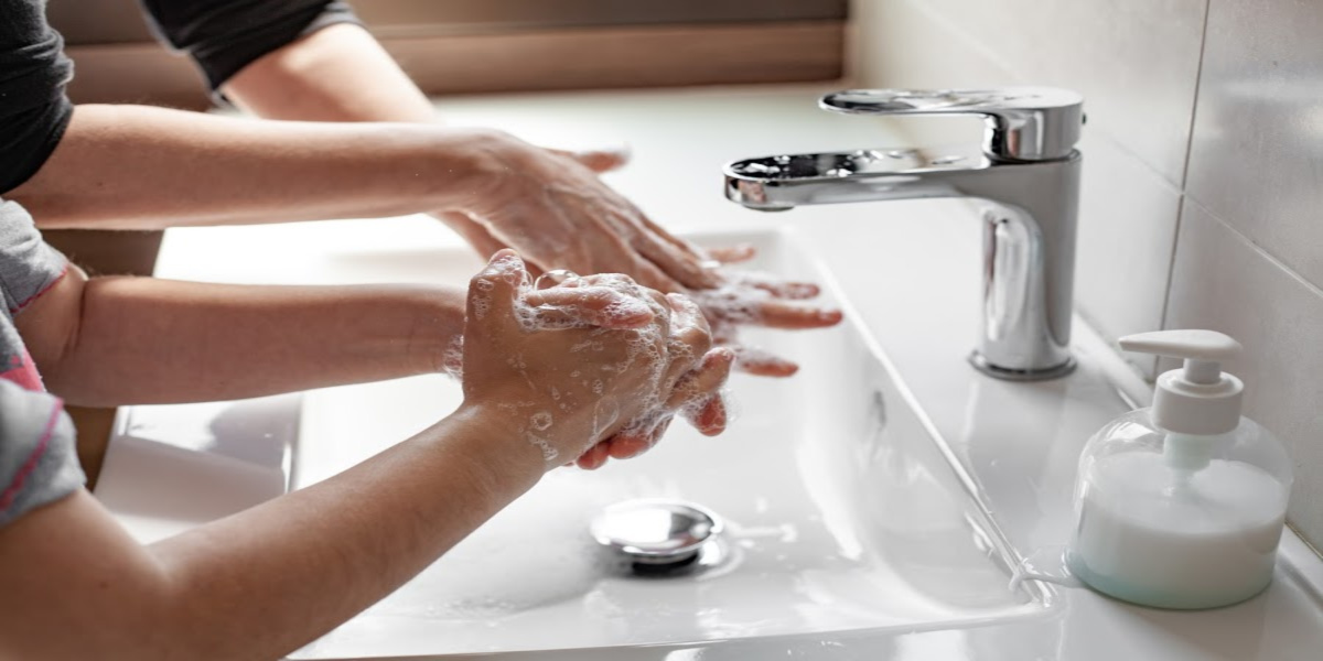 Mother teaching her daughter how to properly wash their hands with soap.